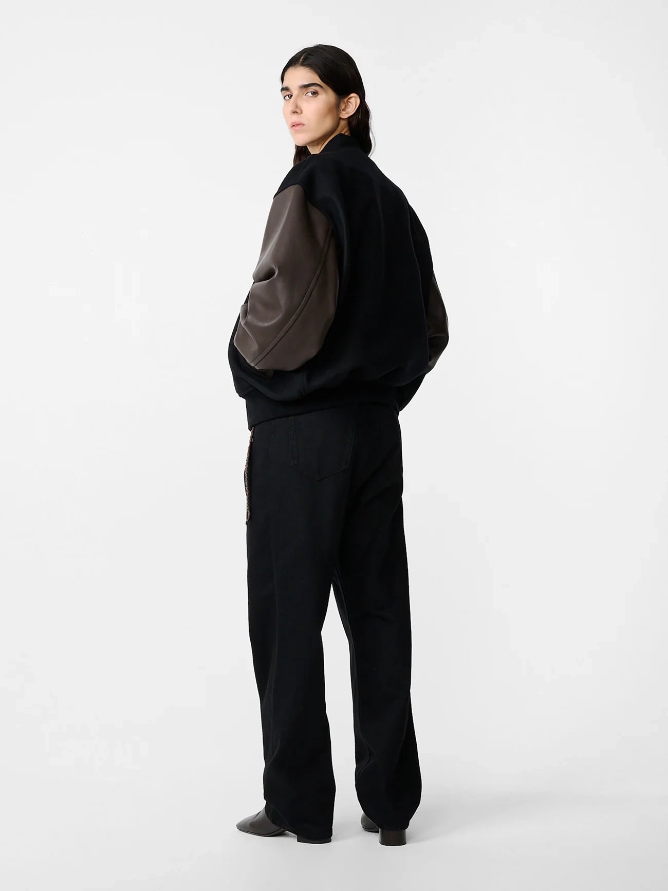 Person wearing a black outfit with a large pocket on a white background