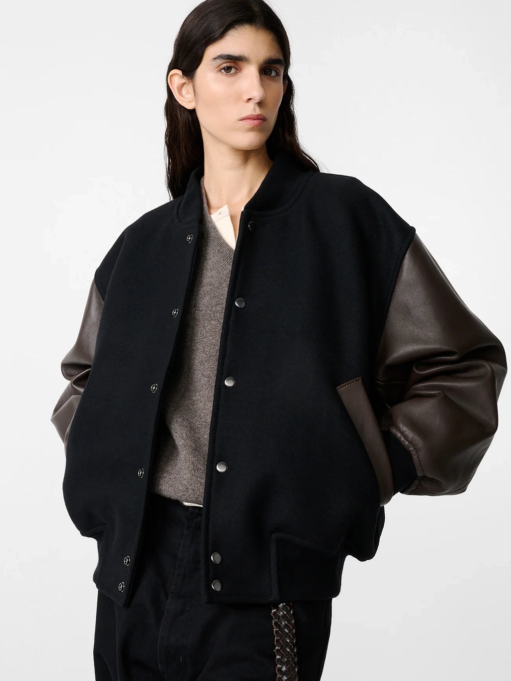Person wearing a black jacket with leather sleeves on a white background
