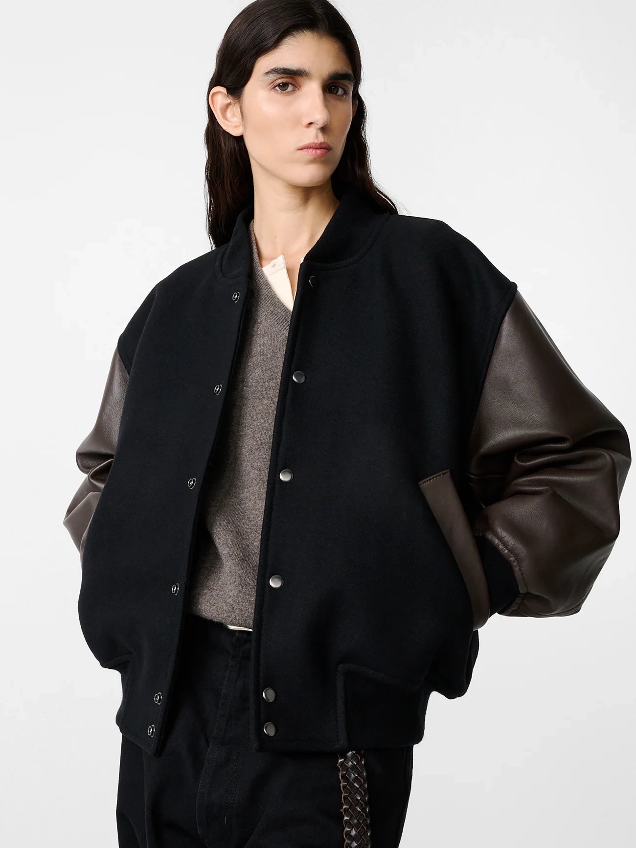 Person wearing a black jacket with leather sleeves on a white background