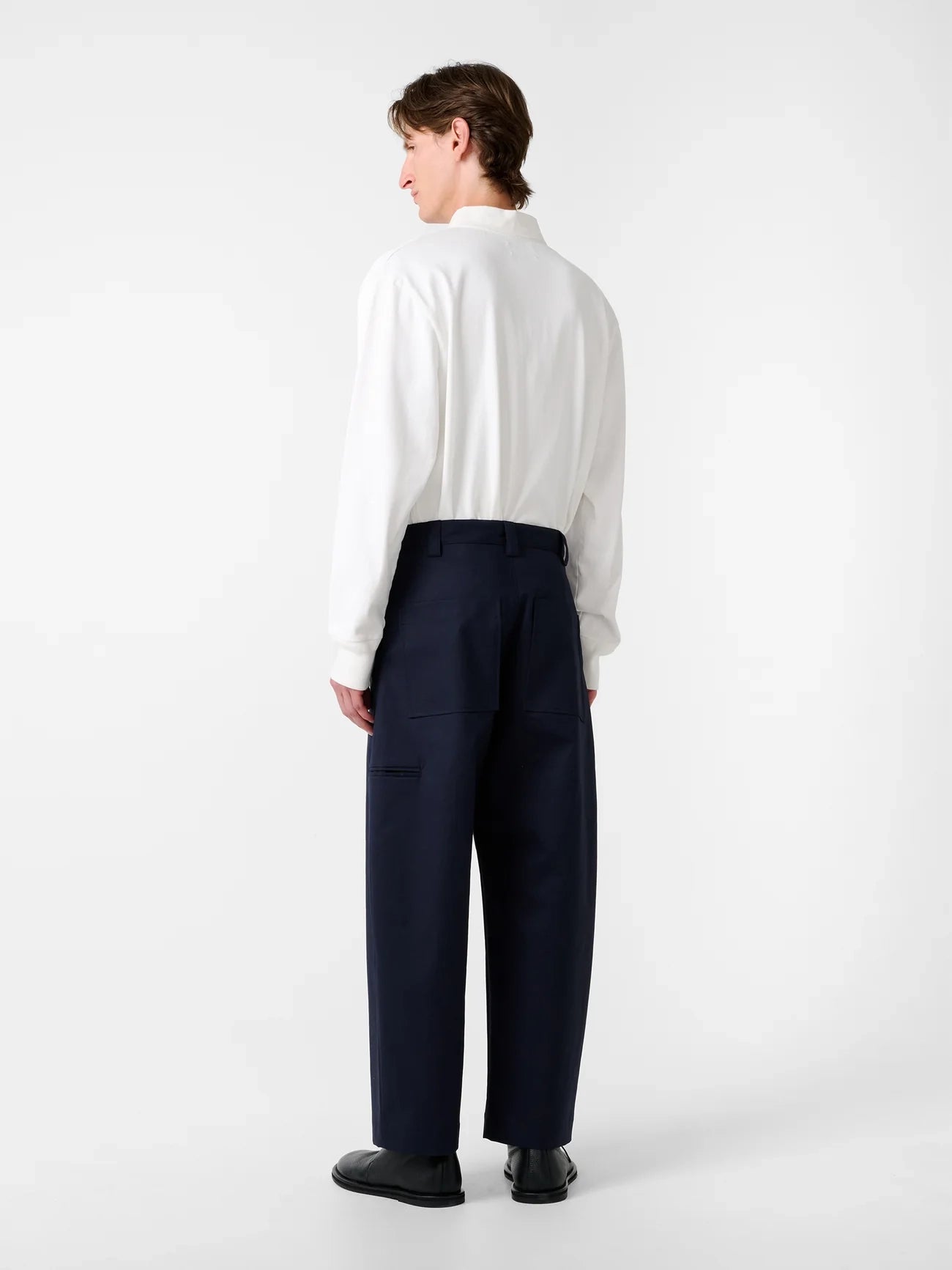 Person wearing a white shirt and navy pants on a white background