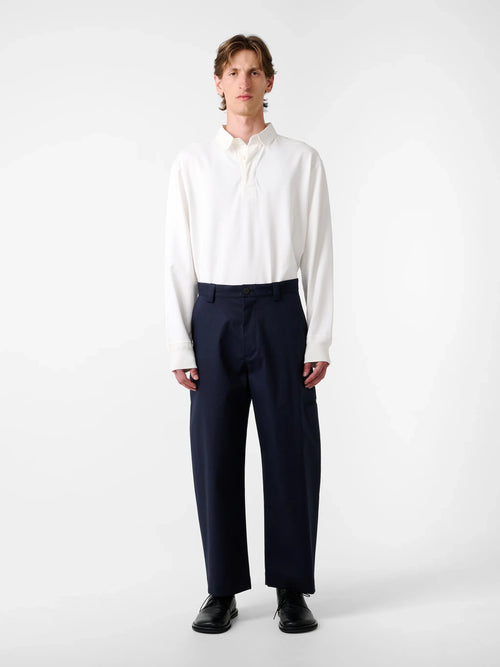 Man wearing a white shirt and navy pants on a white background