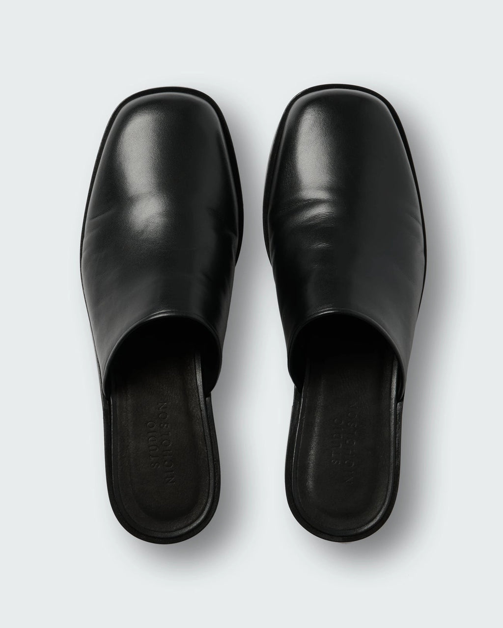 Studio Nicholson Barlow black leather mule with a slip-on design and low stacked heel.