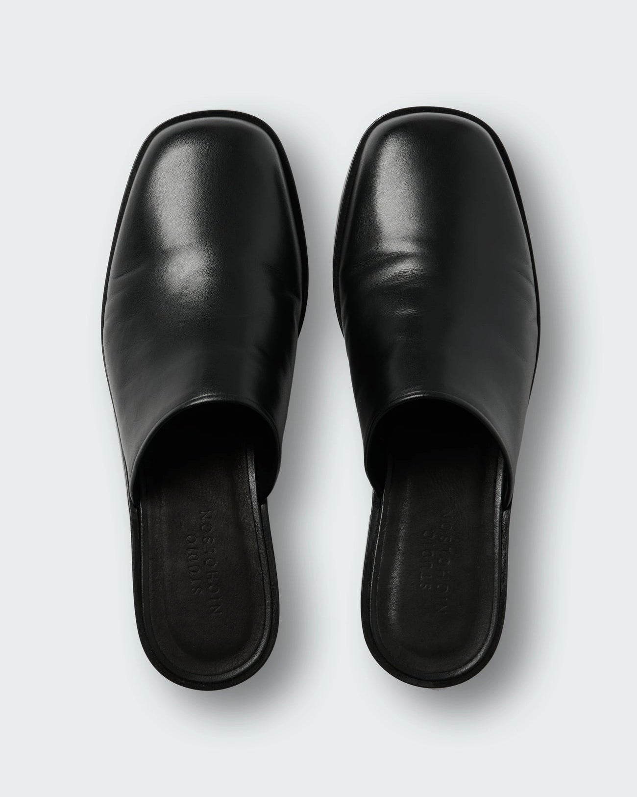 Studio Nicholson Barlow black leather mule with a slip-on design and low stacked heel.