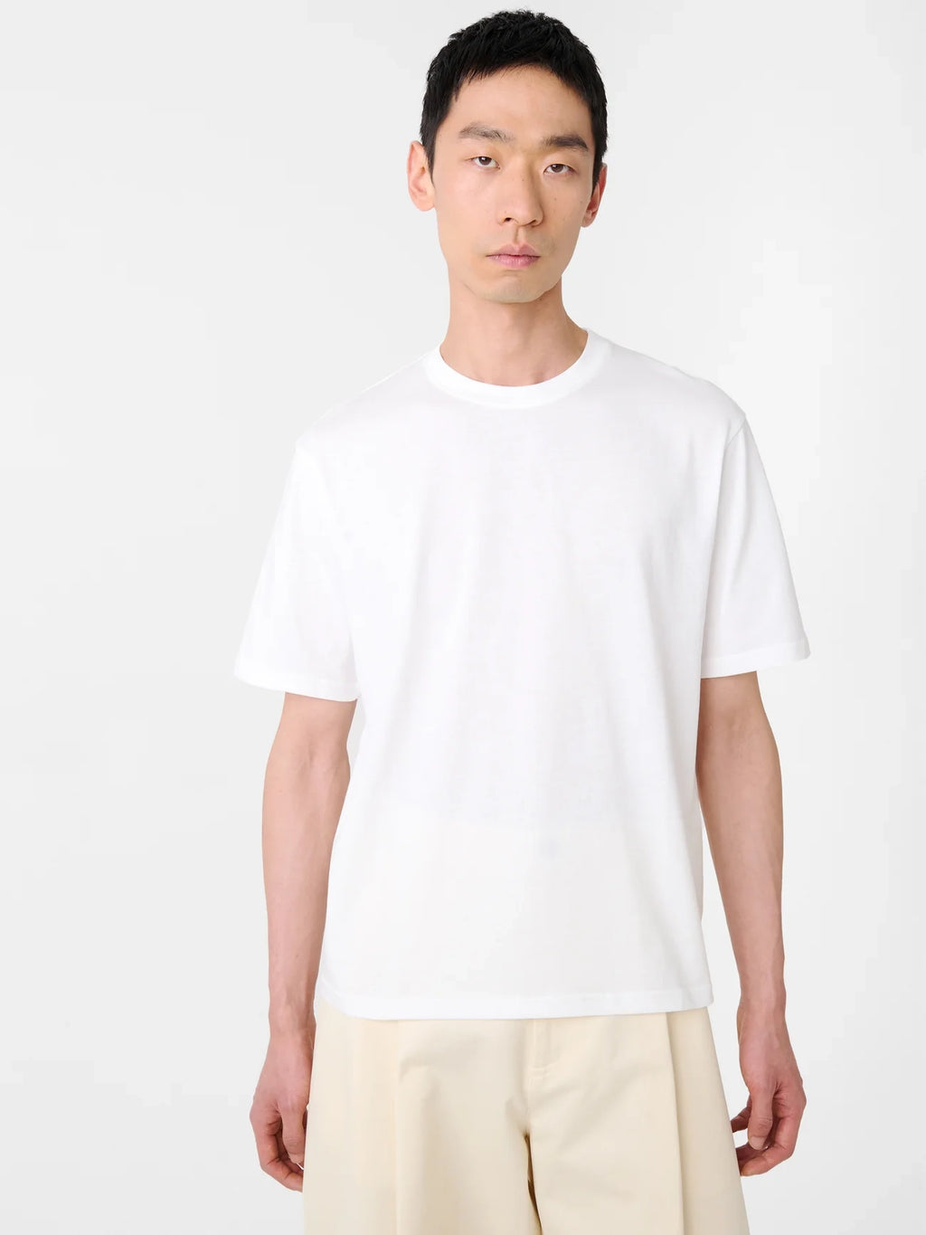 Person wearing a plain white t-shirt and light-colored pants on a white background