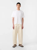 Person wearing a white t-shirt and beige pants on a white background