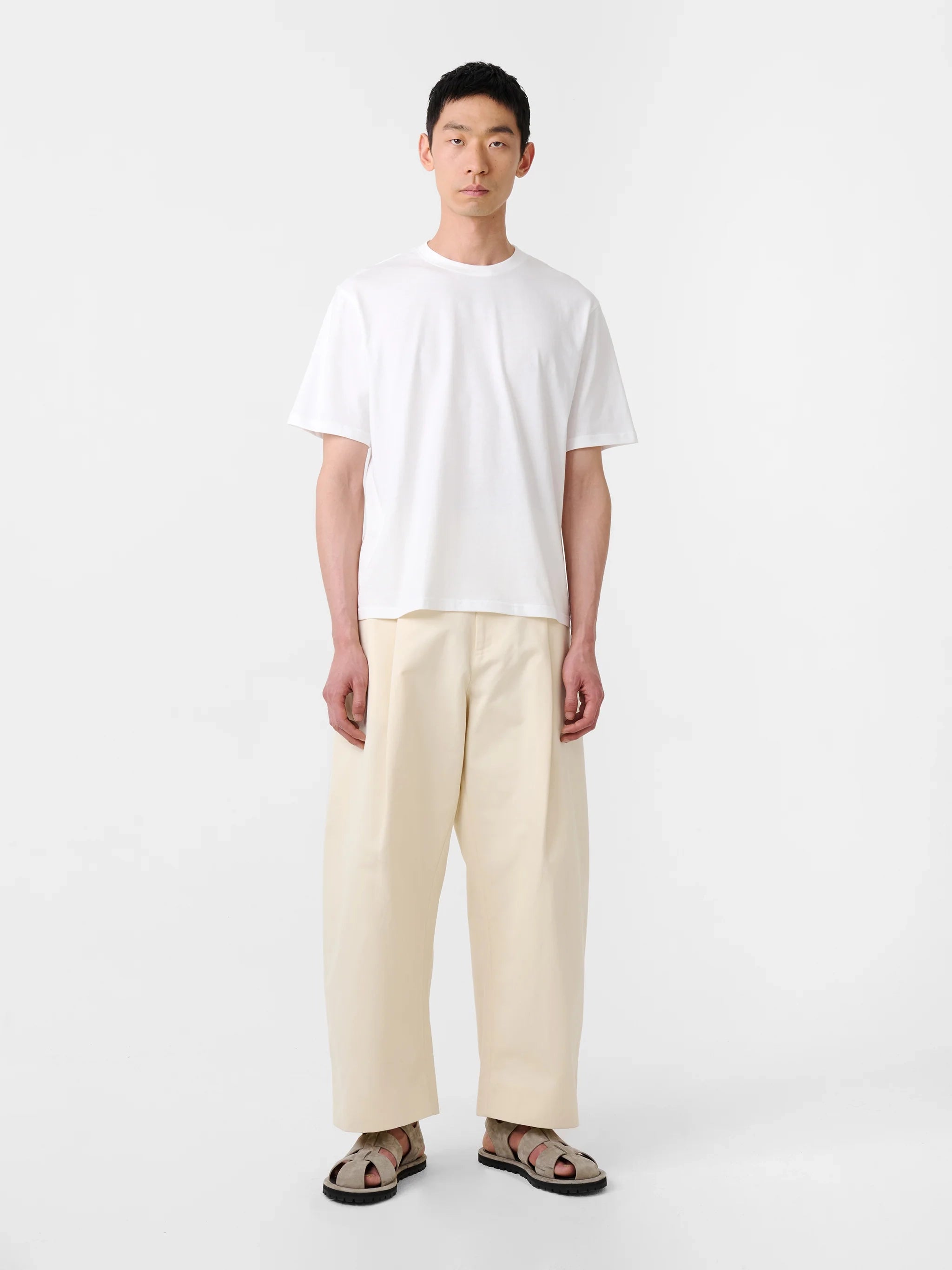 Person wearing a white t-shirt and beige pants on a white background