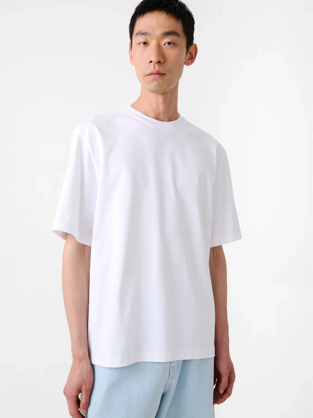 Person wearing a plain white t-shirt against a white background