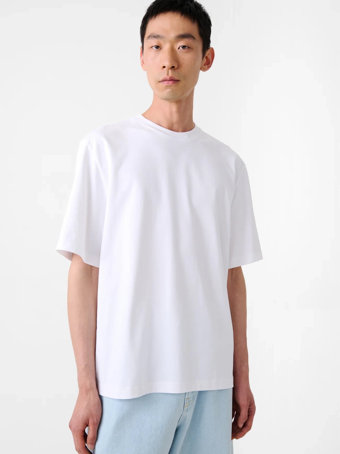 Person wearing a plain white t-shirt against a white background