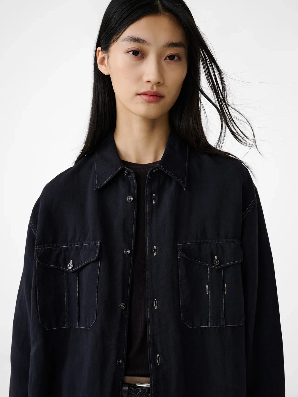 Person wearing a black jacket with a plain background