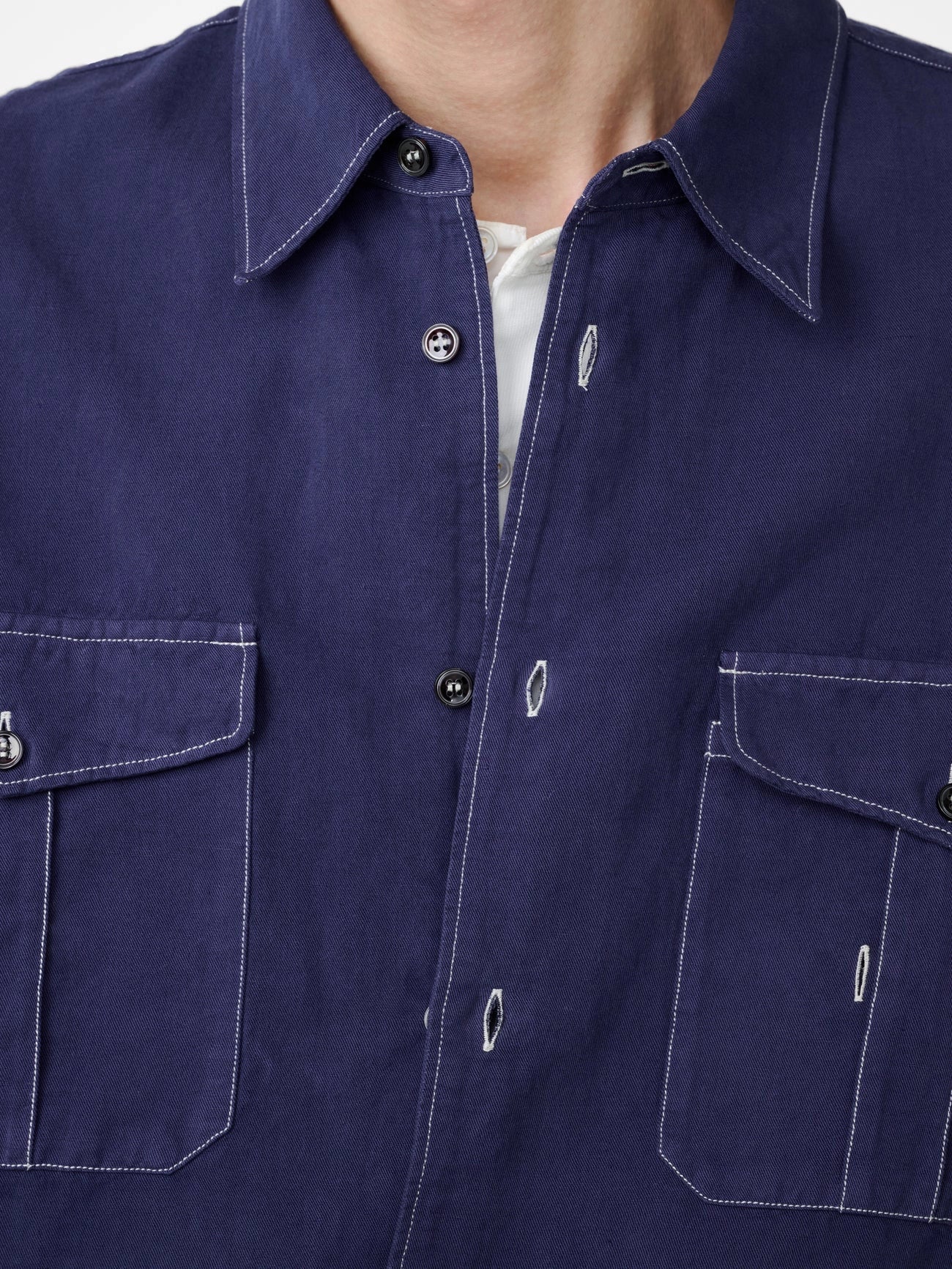 Navy blue shirt with button details on a plain background