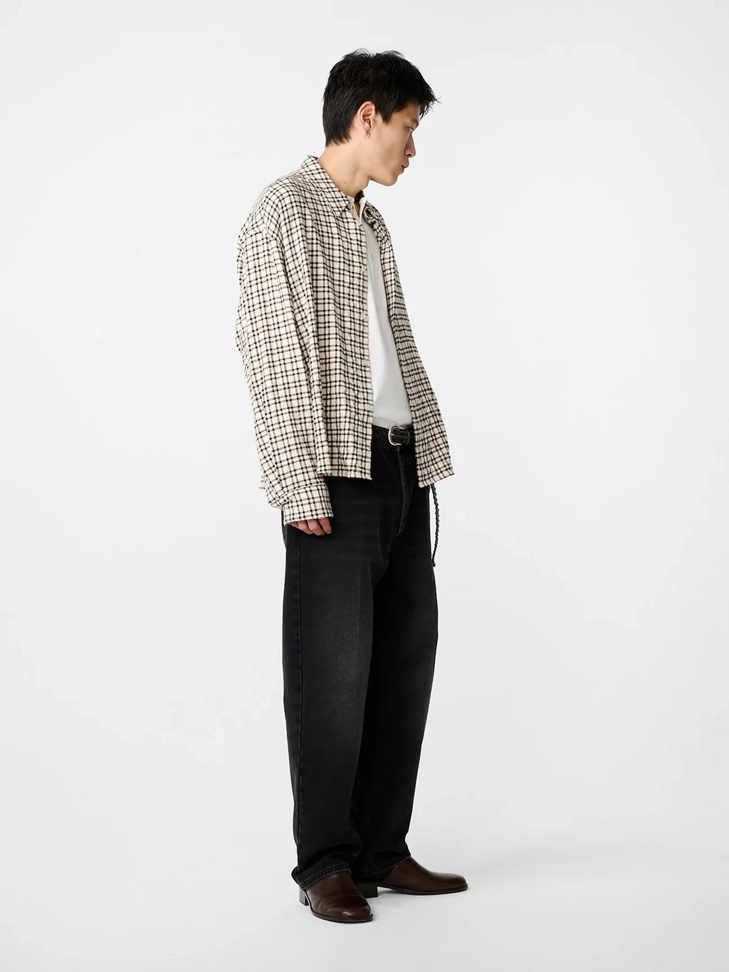 Person wearing a plaid shirt and dark pants on a white background
