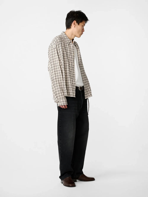 Person wearing a plaid shirt and dark pants on a white background