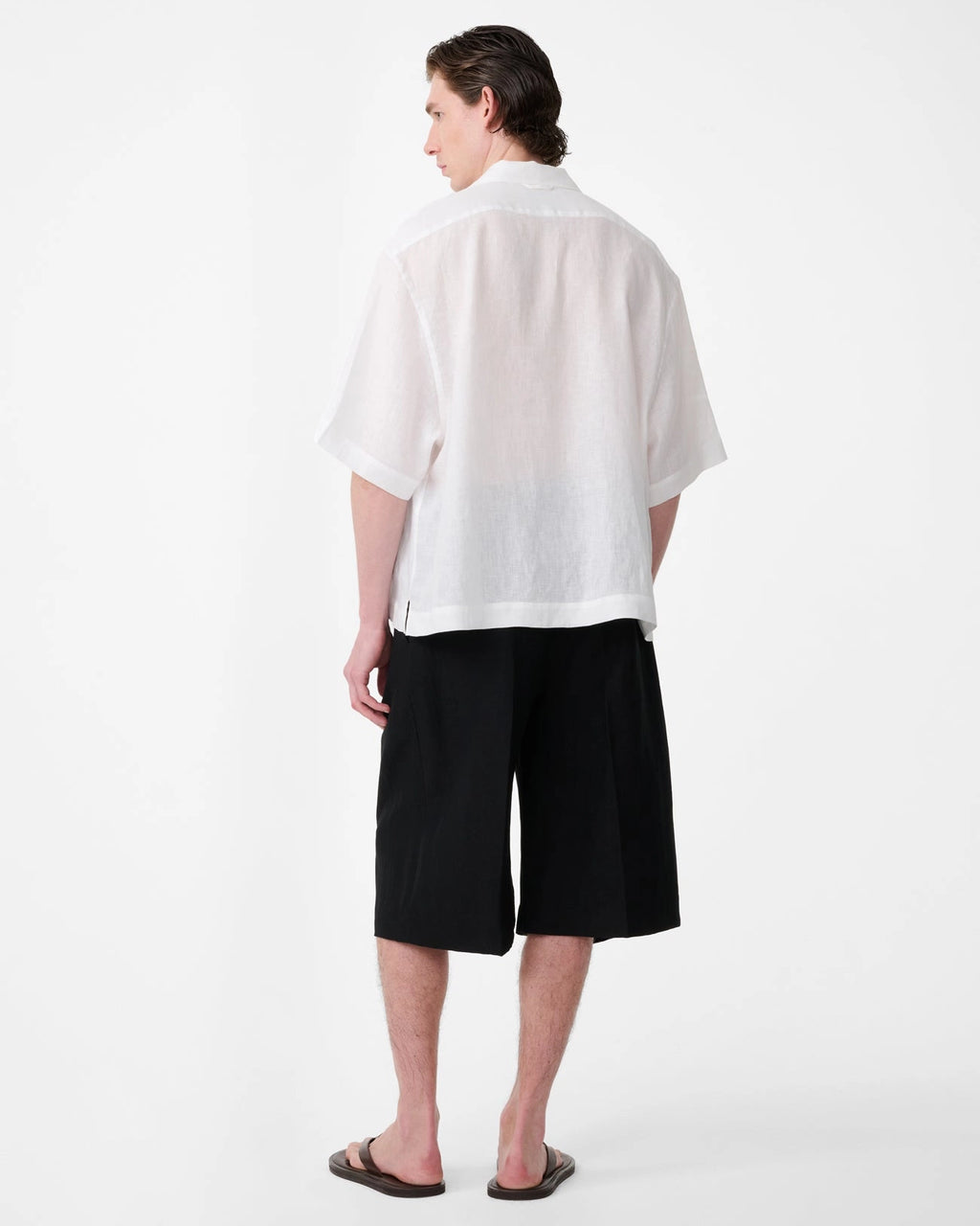 Model wearing Studio Nicholson Oryn white linen short sleeve shirt with a camp collar and straight hem.