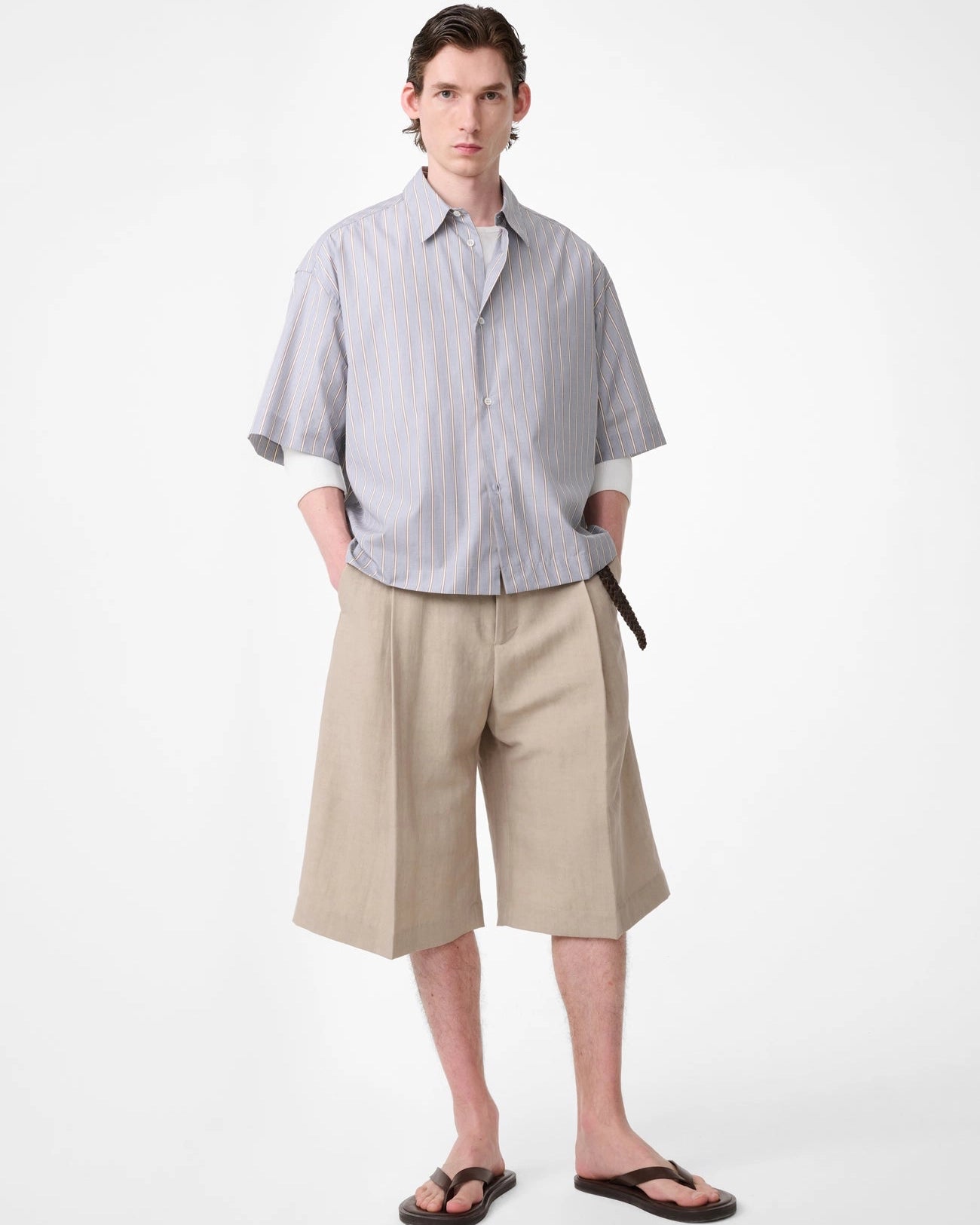 Model wearing Studio Nicholson Sanko short sleeve shirt in grey and brown striped cotton with an oversized fit, point collar and button front.