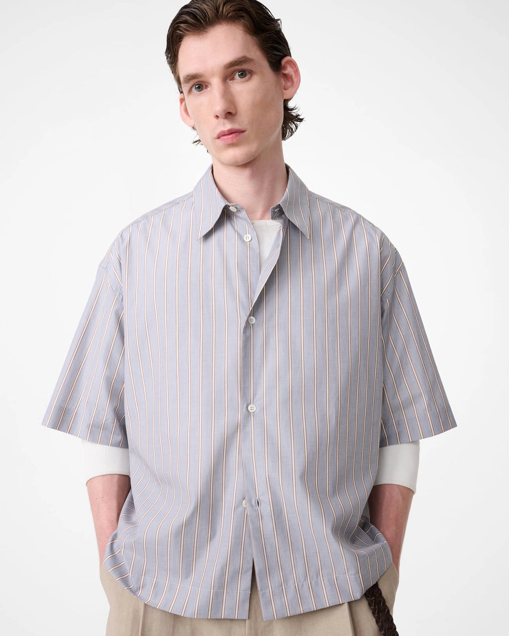Model wearing Studio Nicholson Sanko short sleeve shirt in grey and brown striped cotton with an oversized fit, point collar and button front.