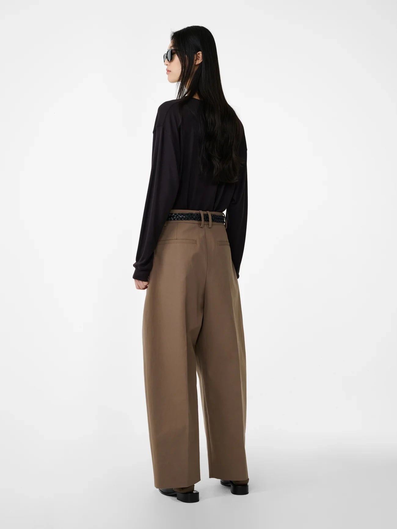 Person wearing a black shirt and brown pants on a white background