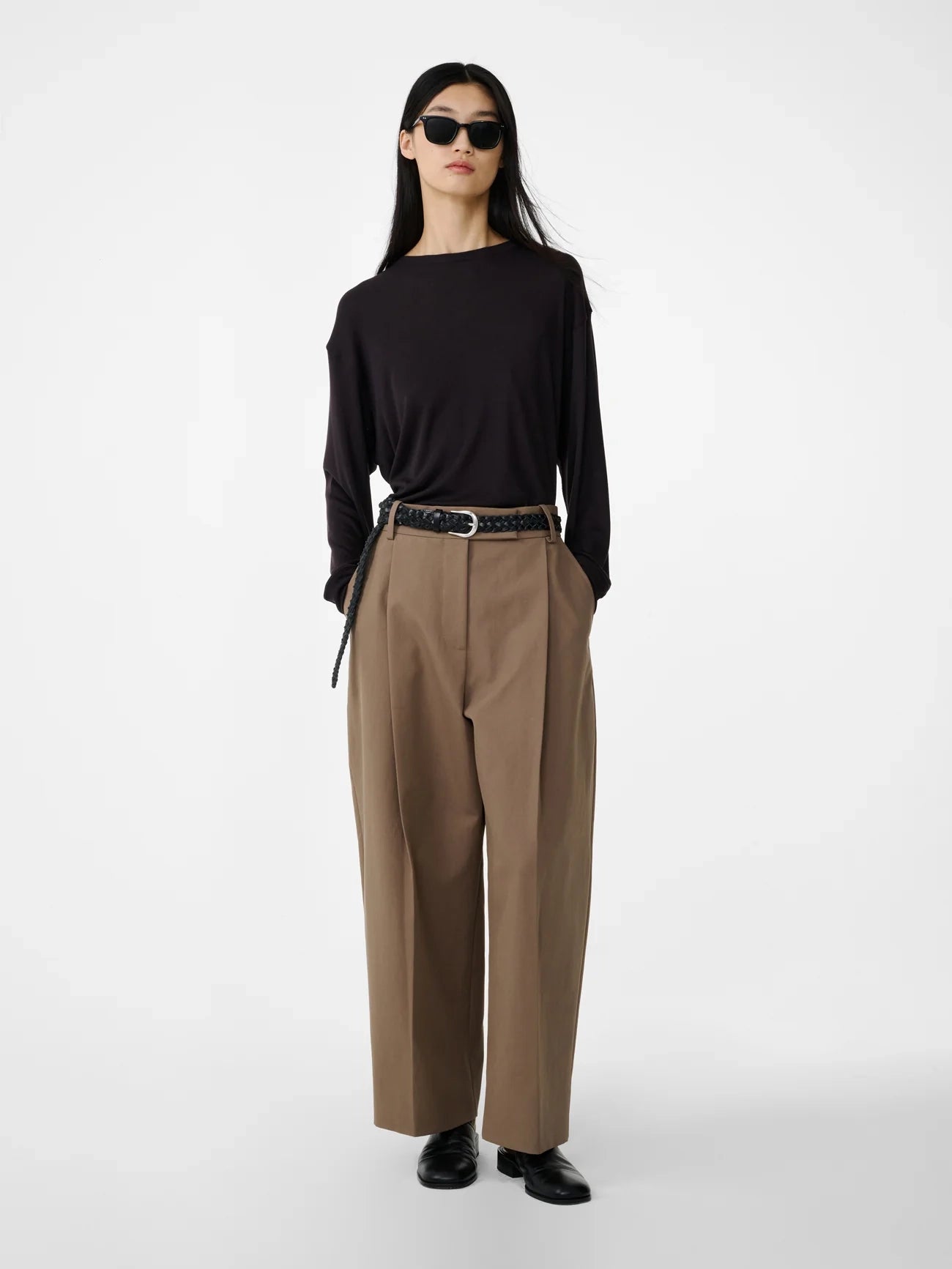 Person wearing a black top and beige pants on a white background