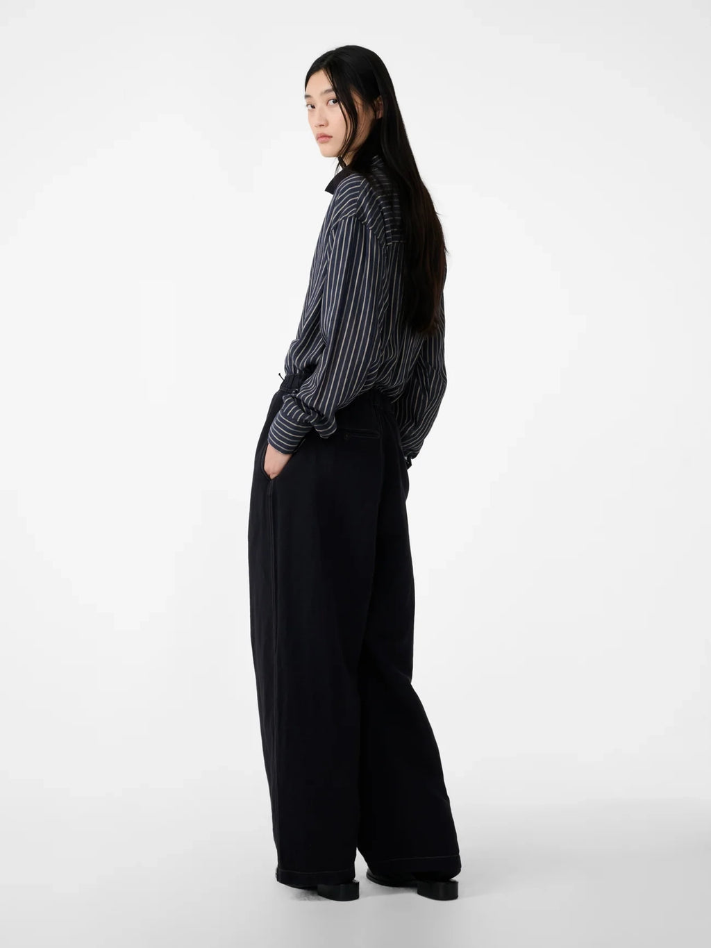 Person wearing a striped shirt and black wide-leg pants on a white background