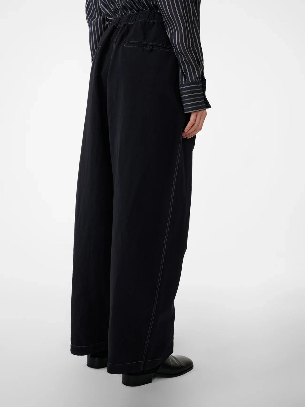 Person wearing black wide-leg pants with a striped shirt on a white background