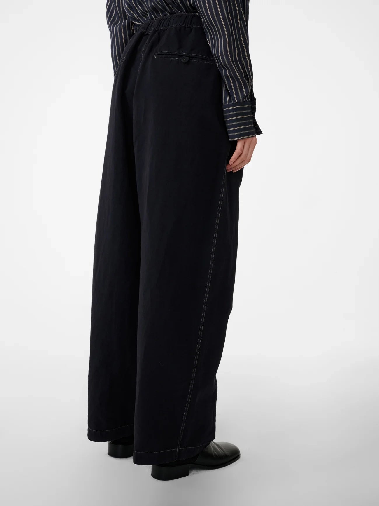 Person wearing black wide-leg pants with a striped shirt on a white background