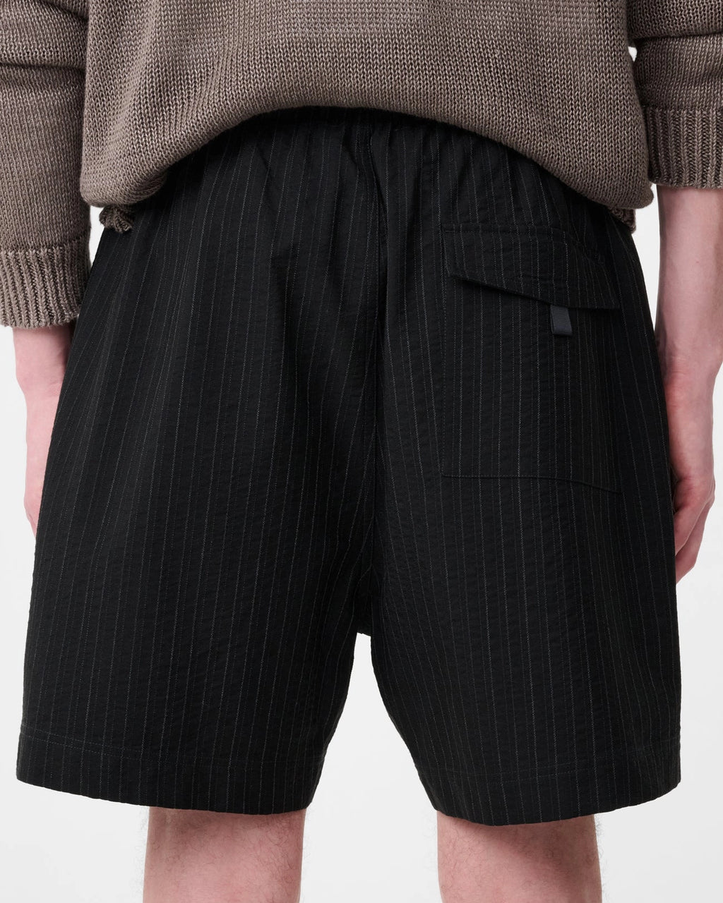 Model wearing Studio Nicholson Starboard black textured wool-cotton drawstring shorts with slip pockets and a back flap pocket.