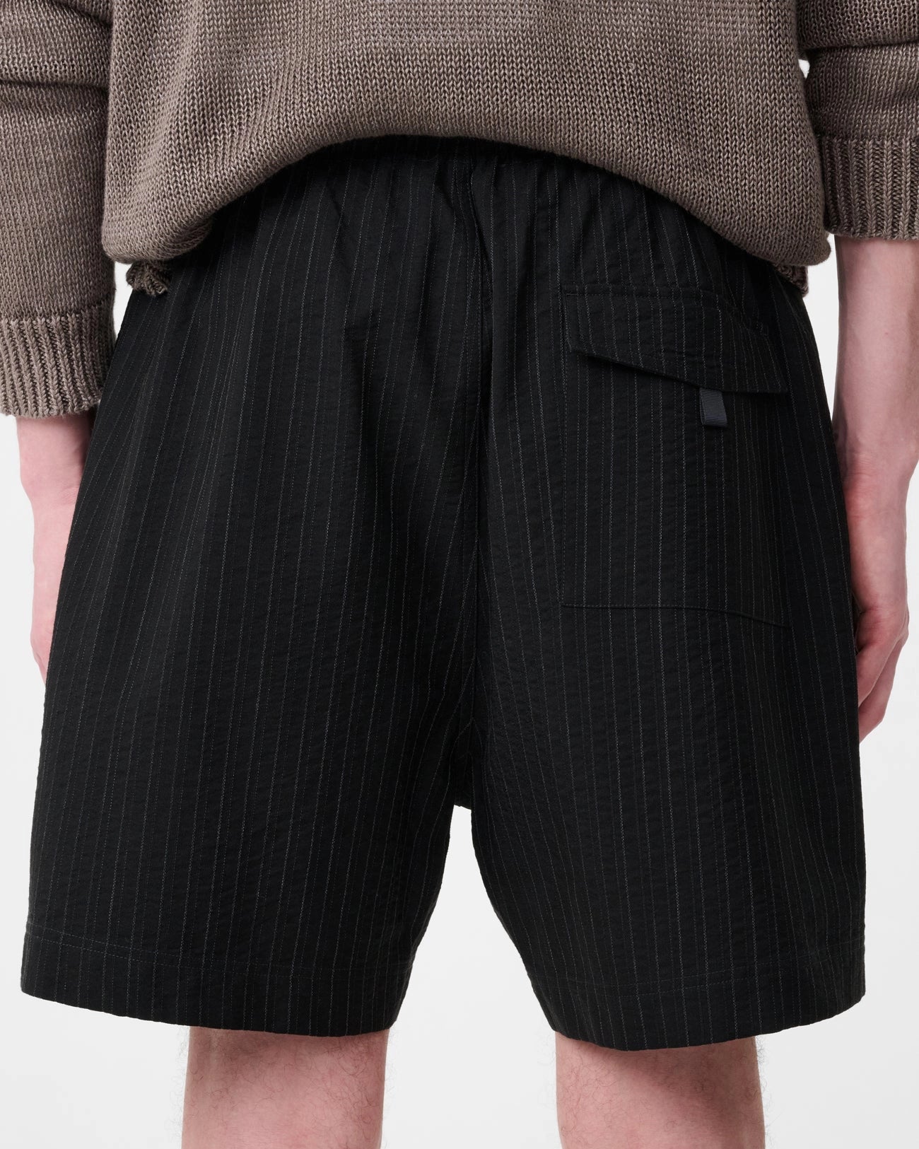Model wearing Studio Nicholson Starboard black textured wool-cotton drawstring shorts with slip pockets and a back flap pocket.