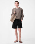 Model wearing Studio Nicholson Starboard black textured wool-cotton drawstring shorts with slip pockets and a back flap pocket.