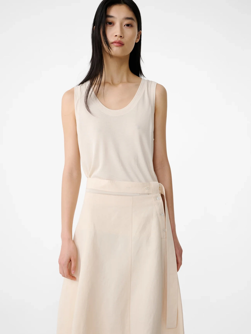 Woman wearing a beige sleeveless top and skirt on a white background