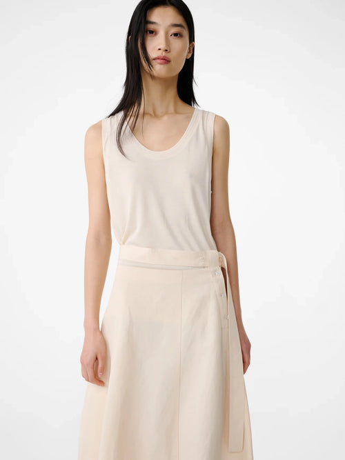 Woman wearing a beige sleeveless top and skirt on a white background