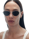 Model wearing THISTLES CRUZ sunglasses in silver titanium with an oval wire frame silhouette and dark green G15 lenses.