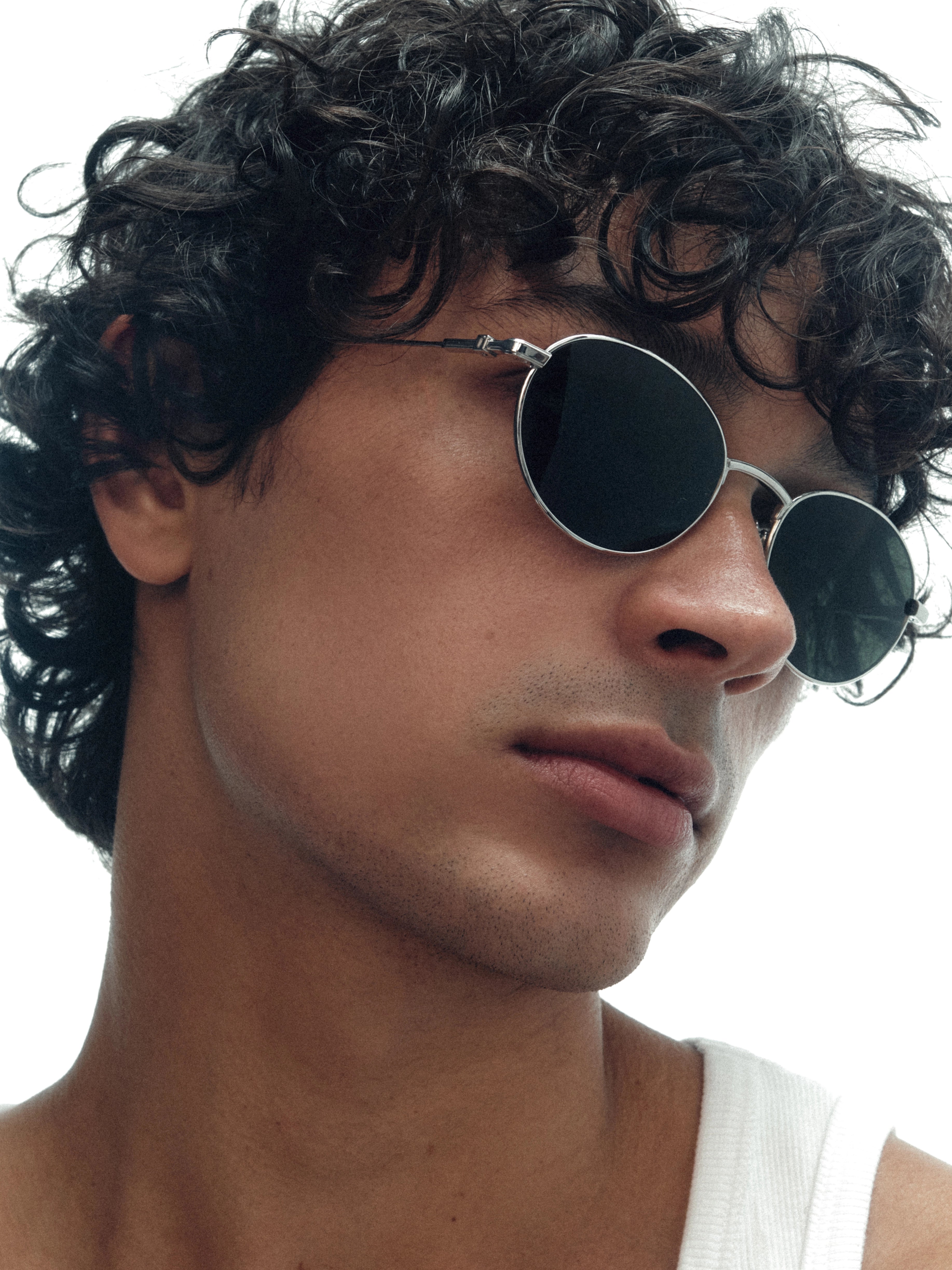Model wearing THISTLES CRUZ sunglasses in silver titanium with an oval wire frame silhouette and dark green G15 lenses.