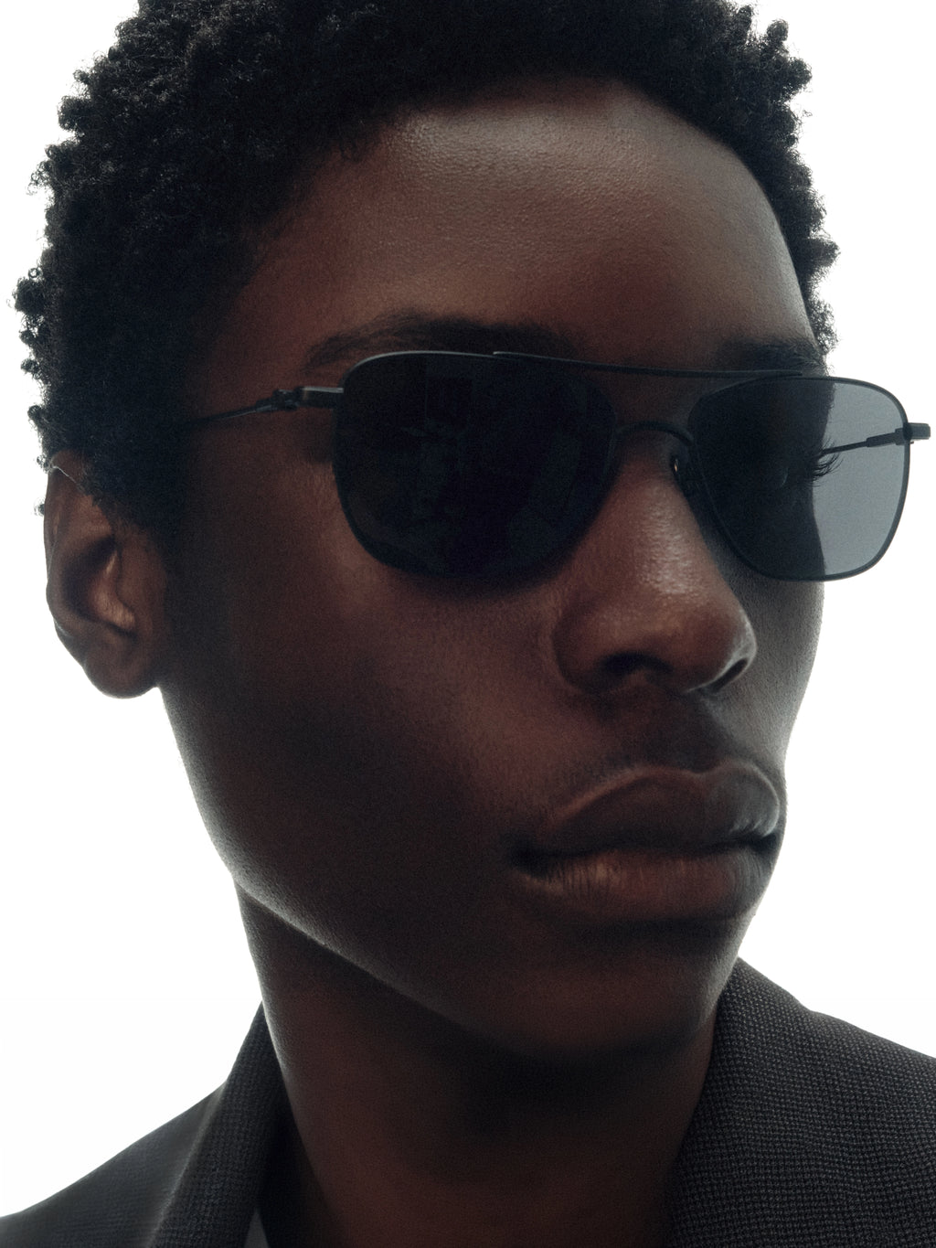 Model wearing THISTLES MALONE sunglasses in black titanium with a rectangular wire frame, double brow bar and dark lenses.