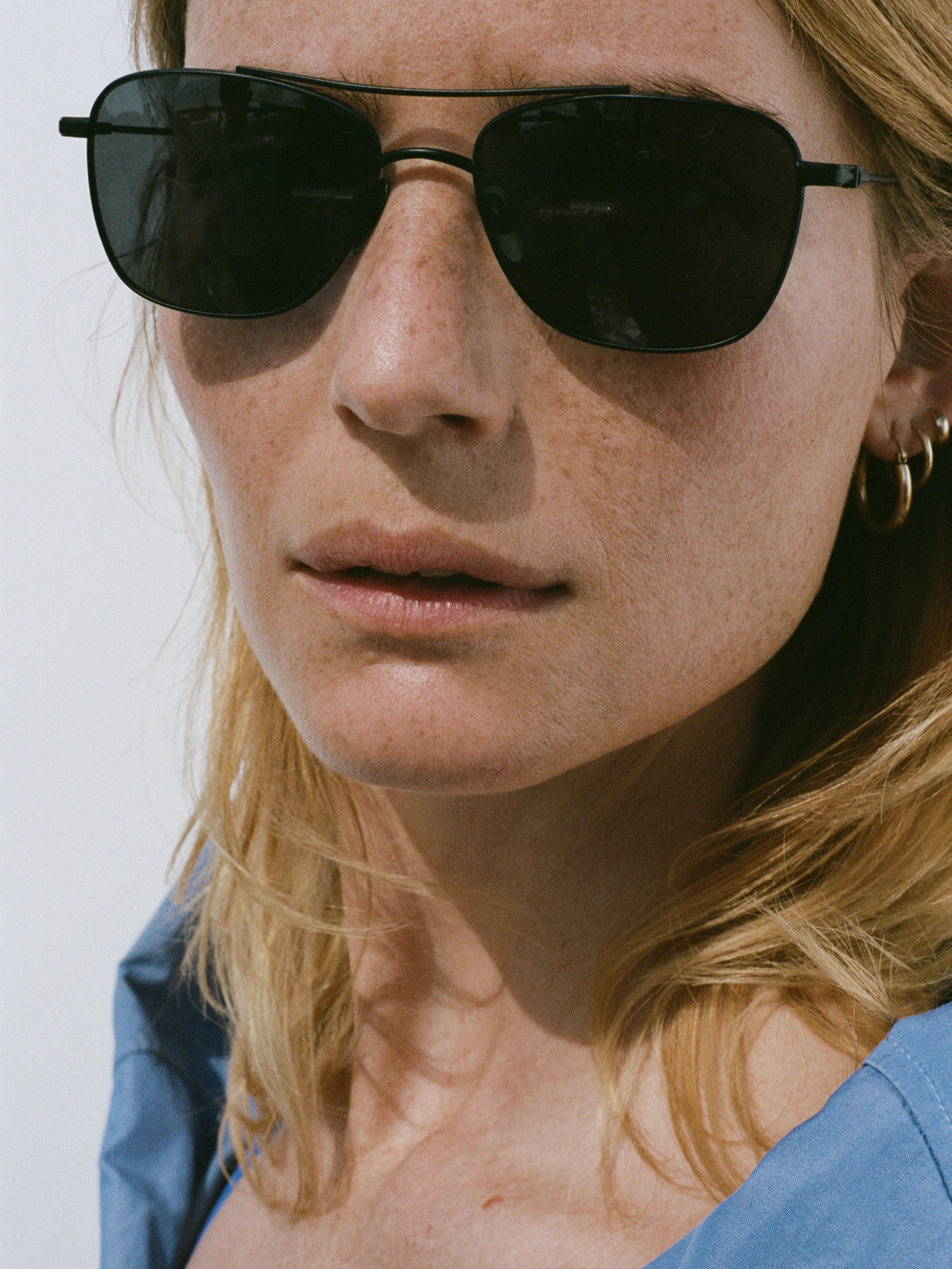 Model wearing THISTLES MALONE sunglasses in black titanium with a rectangular wire frame, double brow bar and dark lenses.